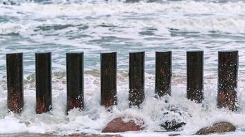 alti frangiflutti in legno nelle spumeggianti onde del mare foto