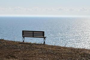 vuoto panchina su scogliera prima mare sfondo, tranquillo, calmo e silenzioso posto per pensiero solo foto