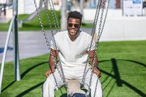 sorridente uomo seduta su un' swing su il erba nel pubblico parco foto