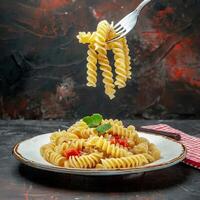 superiore Visualizza Rotini pasta su piatto e su forchetta su buio isolato superficie foto