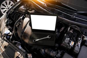 un' il computer portatile con un' vuoto bianca schermo e un' chiave inglese su un' auto motore , auto riparazione e auto Manutenzione manutenzione concetto foto