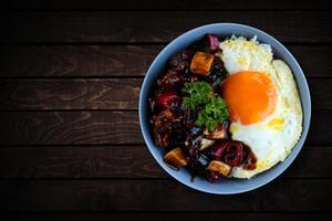 riso nel un' ciotola con soleggiato lato su uovo e fritte pollo con nero Pepe salsa. foto