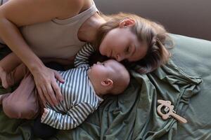 madre e neonato bambino siamo dire bugie su il letto nel il Camera da letto di fronte il finestra foto