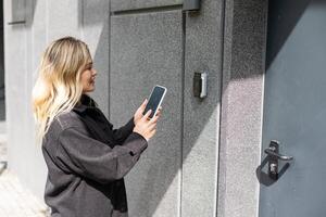 donna Aperto il sicurezza porta con inteligente Telefono foto