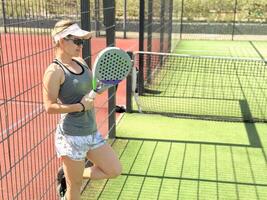 donna giocando padel nel un' erba padel Tribunale interno - giovane sportivo donna padel giocatore colpire palla con un' racchetta foto