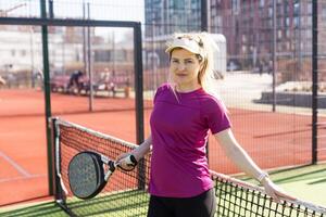 giovane sportivo donna giocando padel gioco nel Tribunale su soleggiato giorno foto