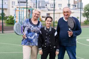 un vecchio coppia e un' nipotina giocare padel tennis foto