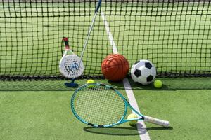 calcio calcio palla pallacanestro tennis palla e racchetta di cui su erba a tramonto foto