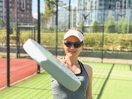 donna giocando padel nel un' erba padel Tribunale interno - giovane sportivo donna padel giocatore colpire palla con un' racchetta foto