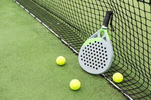 giallo palle su erba torba vicino padel tennis racchetta dietro a netto nel verde Tribunale all'aperto con naturale illuminazione. pagaia è un' racchetta gioco. professionale sport concetto con copia spazio. foto