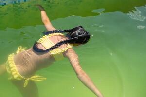 poco ragazza nel il verde acqua di molto sporco piscina foto