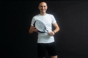 padel tennis giocatore con racchetta nel mani. pagaia tennis, su un' nero sfondo. foto