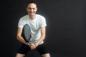 ritratto di uomo giocando pagaia tennis nel posizione per colpire un' rovescio palla nero isolato sfondo. davanti Visualizza. foto