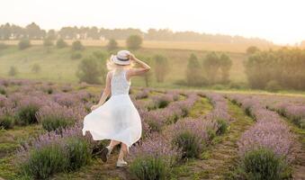 bellissimo giovane donna nel di vimini cappello e bianca vestito nel un' lavanda campo con foto