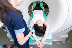 bello, giovane donna andando attraverso un' informatizzato assiale tomografia gatto scansione medico test visita medica nel un' moderno ospedale foto