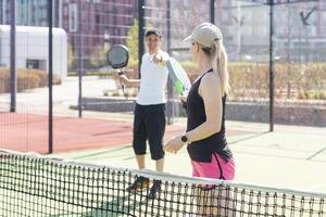 giovane donna giocando padel tennis con compagno nel il Aperto aria tennis Tribunale foto