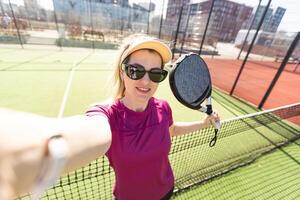 attivo giovane donna provando per battere il palla di padel racchetta mentre giocando tennis nel il Tribunale foto