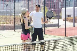 giovane donna giocando padel tennis con compagno nel il Aperto aria tennis Tribunale foto
