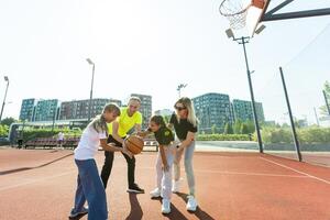 estate vacanze, sport e persone concetto - contento famiglia con palla giocando su pallacanestro terreno di gioco foto