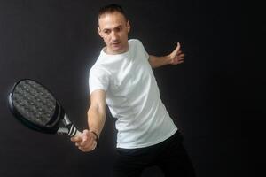 padel tennis giocatore con racchetta nel mani. pagaia tennis, su un' nero sfondo. foto