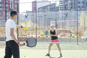 ritratto di Due sorridente dello sportivo in posa su padel Tribunale all'aperto con racchette - padel Giocatori foto