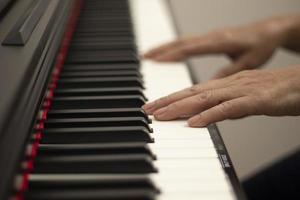 le mani femminili suonano il piano elettrico, i tasti della mano e del pianoforte si chiudono foto