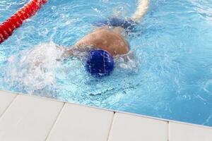 un' pensionato di 70 anni riposa e nuotate nel il piscina nel un' pulire, blu piscina nel il fresco aria su vacanza. foto