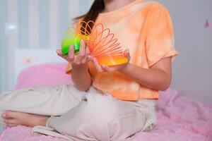 bambino giocando arancia e verde stretto, colorato flessibile figli di giocattolo, divertimento plastica giocattolo. adolescente ragazza giochi viscido foto