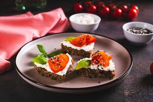 appetitoso crostini su segale pane nel il forma di un' cuore con ricotta e pomodori su un' piatto foto