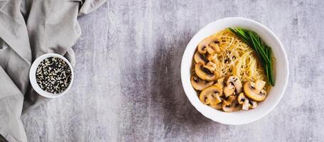 asiatico la minestra con riso tagliatelle, funghi e verde cipolle nel un' ciotola superiore Visualizza ragnatela bandiera foto