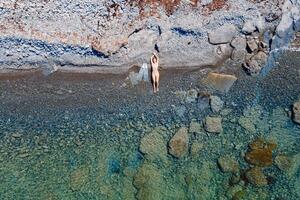 apneista donna con pinne in posa su pietroso mare costa. aereo Visualizza foto