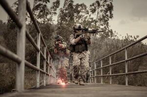 soldati nel camuffare uniformi mirando con loro fucili pronto per fuoco durante militare operazione nel il foresta , soldati formazione nel un' militare operazione foto