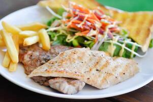 Maiale bistecca e pollo bistecca con francese patatine fritte ,pane e insalata o grigliato Maiale e grigliato pollo con fritte Patata foto