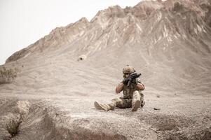 soldati nel camuffare uniformi mirando con loro fucili pronto per fuoco durante militare operazione nel il deserto , soldati formazione nel un' militare operazione foto