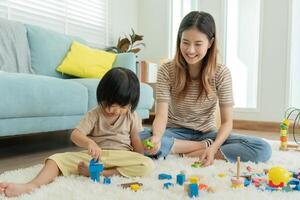 contento Asia madre giocare e imparare giocattolo blocchi con il poco ragazza. divertente famiglia è contento e eccitato nel il Casa. madre e figlia avendo divertimento la spesa tempo insieme. vacanza, attività, sviluppo foto