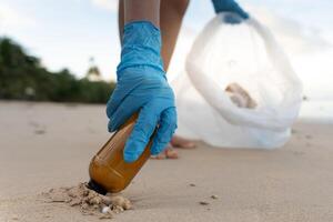 Salva oceano. volontario raccogliere su spazzatura spazzatura a il spiaggia e plastica bottiglie siamo difficile decomporsi impedire danno acquatico vita. terra, ambiente, greening pianeta, ridurre globale riscaldamento, Salva mondo foto