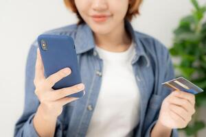 donna utilizzando smartphone per in linea shopping a casa. mano Tenere mobile Telefono con pagamento dettaglio pagina Schermo e credito carta, restare casa, tecnologia, elettronico commercio, Internet, mercato posto foto