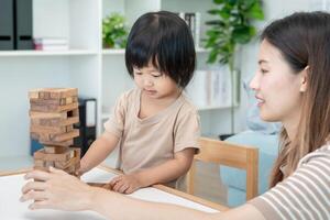 contento Asia madre giocare e imparare giocattolo blocchi con il poco ragazza. divertente famiglia è contento e eccitato nel il Casa. madre e figlia avendo divertimento la spesa tempo insieme. vacanza, attività, sviluppo foto