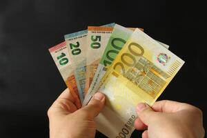 uomo conteggio Euro i soldi con il suo mano. Euro banconote. il carta moneta di europeo unione .calcolatrice nel il sfondo. foto