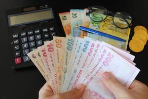 il carta moneta di tacchino. calcolatrice nel il sfondo.turco lira banconote. uomo conteggio Turco i soldi con il suo mano. foto