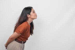 carino asiatico donna nel Marrone camicia invio soffiaggio bacio con broncio labbra per sua lato isolato su bianca sfondo. foto
