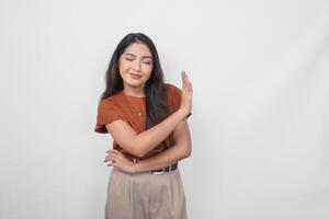 un' giovane asiatico donna indossare Marrone camicia fare fermare cartello con palma di il mano al di sopra di bianca isolato sfondo. foto