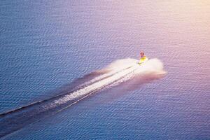 bicicletta d'acqua, moto d'acqua galleggia su il acqua illuminato di il luce del sole foto