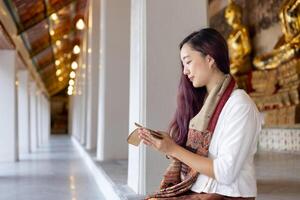 asiatico buddista donna lettura sanscrito antico palma foglia manoscritto di tripitaka il signore Budda dhamma insegnamento mentre seduta nel tempio su santo pieno Luna giorno per canto e culto nel il monastero foto