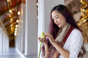 buddista asiatico donna nel tradizionale stoffa è pieghevole loto foglia nel buddista tempio come meditazione processi per pace e tranquillo religione pratica foto