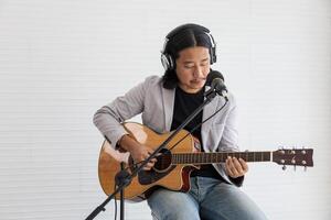 asiatico artista cantando canzone e giocando acustico chitarra su bianca sfondo per vivere acustico concerto e musica relazionato concetto foto
