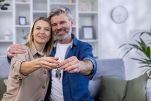 selezionato messa a fuoco, anziano dai capelli grigi coppia, uomo e donna abbracciare insieme nel nuovo appartamento Casa, contento famiglia Tenere Casa chiavi. foto