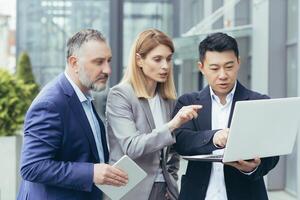 diverso gruppo di attività commerciale le persone, maschio e femmina, insieme al di fuori ufficio di brainstorming soluzioni, squadra di colleghi guardare a il computer portatile schermo pensiero di attività commerciale strategia foto