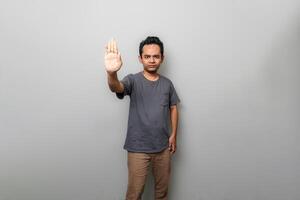 asiatico uomo nel grigio è Esprimere a gesti per fermare qualcosa foto
