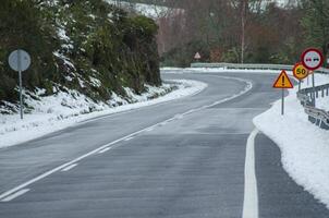 curva con Pericolo segni su un' strada su un' nevoso giorno nel inverno foto